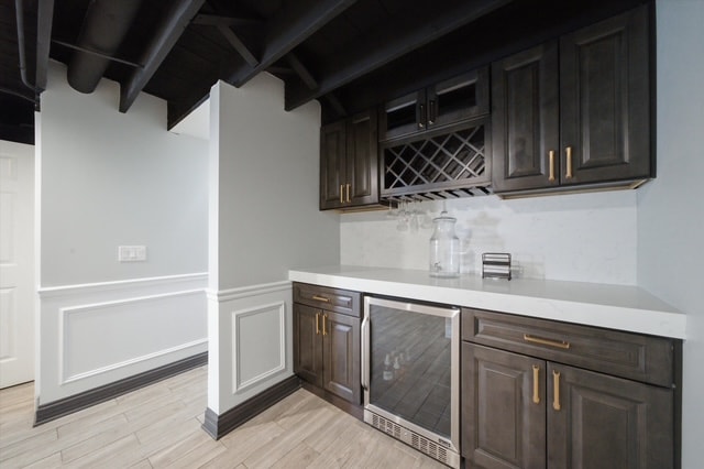 Basement dry bar with dark cabinets, wine rack and mini fridge