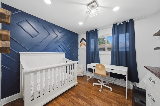 Bedroom with navy accent wall, crib and desk